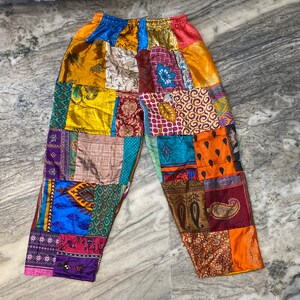 May include: Multicolored patchwork pants with a variety of floral and geometric patterns. The pants are made from different fabrics and sewn together in a random pattern.