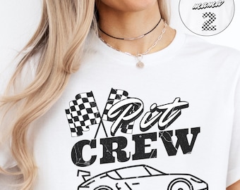 May include: White t-shirt with a black and white checkered flag, a black and white race car, and the text "Pit Crew" in black.