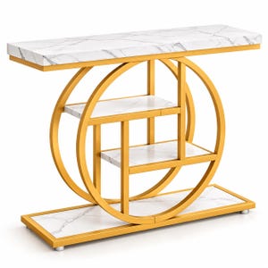 May include: A console table featuring a gold-colored metal frame with a circular design and white faux marble surfaces. The unit includes a rectangular top shelf, two interior shelves within the circular frame, and a rectangular base shelf.