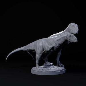 May include: A grey, detailed, 3D printed model of two dinosaurs standing on a circular base. The dinosaurs are posed in a playful, almost affectionate manner, with one dinosaur's head resting on the other's back.