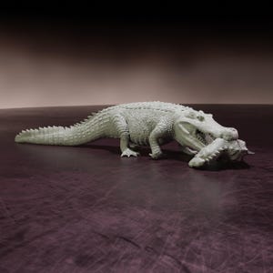 Puede incluir: Una escultura detallada de un caimán en pose de depredador, con las mandíbulas abiertas, sosteniendo un animal más pequeño. El caimán es de color gris claro, con piel texturizada y dientes afilados. El fondo es un degradado de marrón y morado.