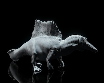 Puede incluir: Un juguete de dinosaurio Spinosaurus gris con una gran aleta dorsal, de pie sobre una superficie negra reflectante. El juguete tiene detalles, incluyendo un hocico largo y garras visibles. El fondo es negro sólido.