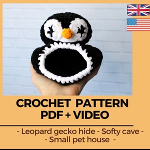 May include: A handmade black and white crochet penguin-shaped pet house. The penguin has white eyes, an orange beak, and a white trim around the opening. The text "CROCHET PATTERN PDF + VIDEO" is displayed below the penguin.
