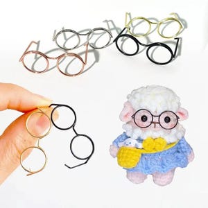 May include: A set of four pairs of glasses in different colors and styles. The glasses are made of metal and have round lenses. The glasses are arranged in a row on a white background.