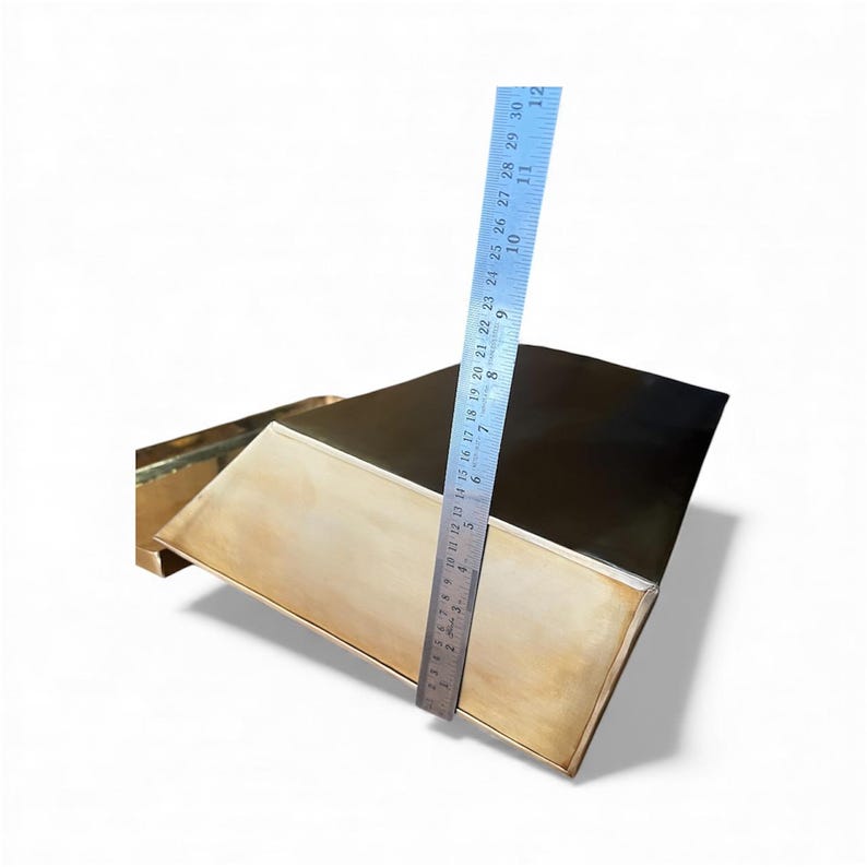 May include: A rectangular brass tray with a polished finish, positioned next to a metal ruler that shows the tray has a height of approximately 12 inches. The tray features a flat base and angled sides, reflecting light across its smooth surface.