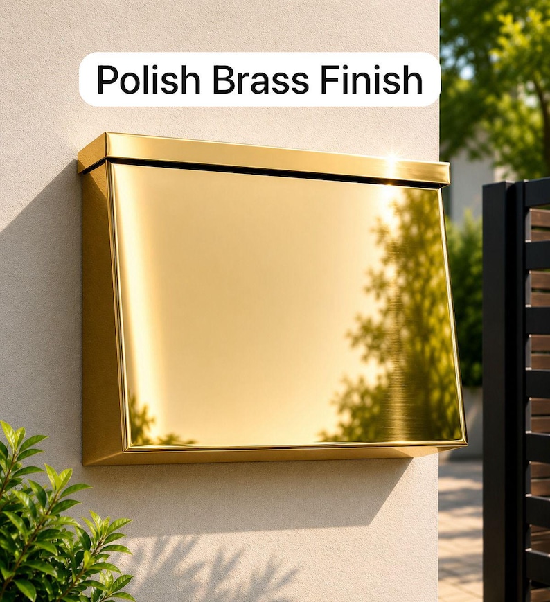 May include: A rectangular wall-mounted mailbox with a highly reflective, polished brass finish. The mailbox features a flat top lid and a smooth, angled front panel. A white label above the mailbox displays the text Polish Brass Finish.