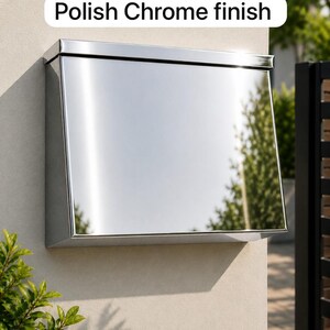 May include: A wall-mounted mailbox with a reflective polish chrome finish. The rectangular metal box features a flat top lid and a smooth, mirrored front surface. The text "Polish Chrome finish" is displayed in a white box above the mailbox.