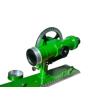 May include: A green surveying instrument with a graduated circle, a telescope, and a base with a ruler. The instrument is used for measuring angles and distances.