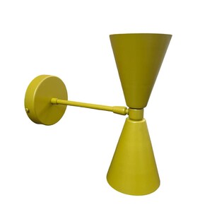 May include: A yellow wall sconce with two cone-shaped shades. The shades are adjustable and can be pointed in different directions.