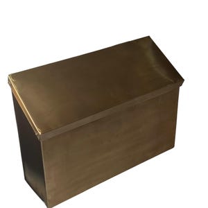 May include: A rectangular metal box with a slanted top lid and a smooth brown finish. The object features a clean, boxy silhouette with sharp edges and a solid, uniform metallic surface color throughout the entire exterior structure.
