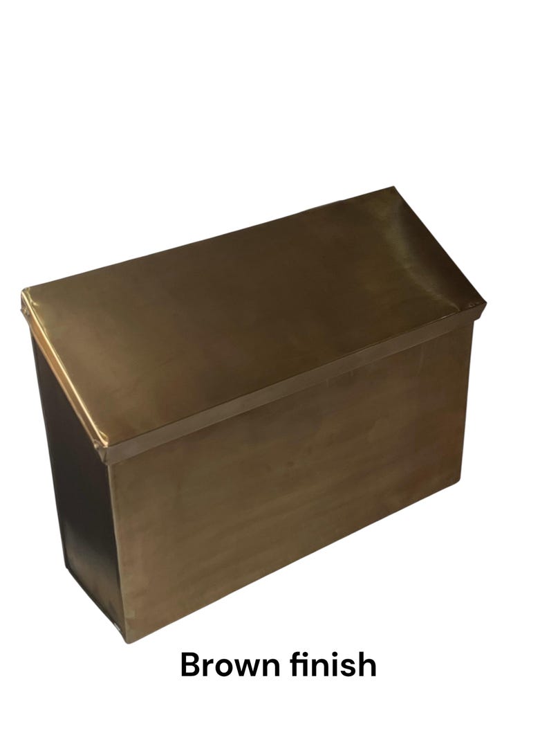 May include: A rectangular metal box with a slanted top lid and a smooth brown finish. The object features a clean, boxy silhouette with sharp edges and a solid, uniform metallic surface color throughout the entire exterior structure.