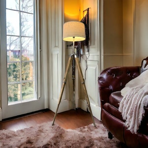 Puede incluir: Un sill&oacute;n de cuero marr&oacute;n con una manta blanca se encuentra en una habitaci&oacute;n con suelo de madera y una alfombra blanca. Una l&aacute;mpara de pie de tr&iacute;pode con una pantalla blanca est&aacute; en la esquina de la habitaci&oacute;n.