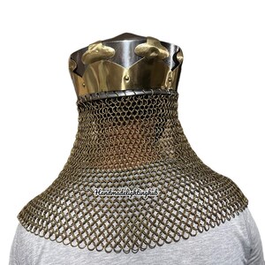 May include: A gold and silver helmet with a chainmail neck guard. The helmet has a pointed top and a decorative band around the base. The chainmail is made of small, interlocking rings.