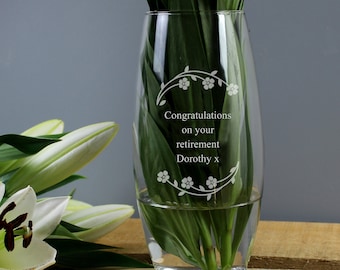May include: A clear glass vase with an etched design of flowers and vines. The vase has the text "Congratulations on your retirement Dorothy x" etched on the front.