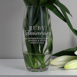 May include: A clear glass vase with the text "RUBY Anniversary 40 WONDERFUL YEARS SANDRA & KEITH MARCH 2022" etched on the side.