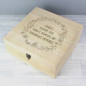May include: A light wood box with a floral design and the text "Louise's Memory Box Today's Moments Are Tomorrow's Memories".
