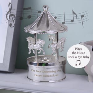 Peut inclure: Carrousel musical argent&eacute; avec une base blanche. La base est grav&eacute;e avec "On Your Christening Day Henry William Scott". Le carrousel joue la chanson "Rock-a-bye Baby".
