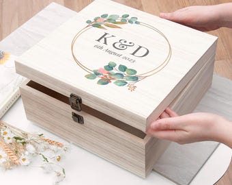 May include: A white wooden keepsake box with a gold-toned circle and floral design. The box has a hinged lid and two clasps. The text "K&D 6th August 2023" is printed on the lid.