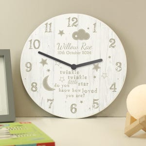 May include: White wooden clock with a beige background and black hands. The clock face has a cloud, stars, and the text "twinkle twinkle little star do you know how loved you are?"  The clock also has the name "Willow Rae" and the date "10th October 2024".