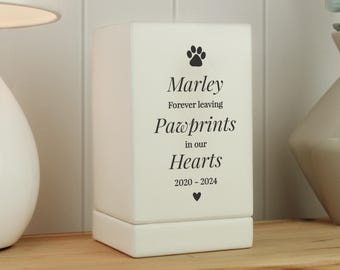 May include: White ceramic memorial candle holder with a paw print and the text "Marley Forever leaving Pawprints in our Hearts 2020 - 2024"