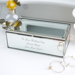 May include: A silver mirrored jewellery box with a clear glass lid. The box has an inscription that reads "On Your Wedding Day Jessica Raine Love From Dad x".