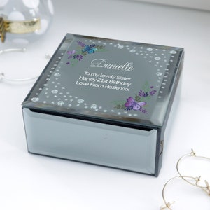 May include: A mirrored jewellery box with a silver glitter finish. The lid features a floral design with butterflies and the text "Danielle To my lovely Sister Happy 21st Birthday Love From Rosie xxx".