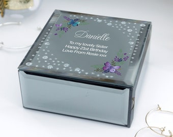 May include: A mirrored jewelry box with a silver glitter finish. The lid features a floral design with butterflies and the text "Danielle To my lovely Sister Happy 21st Birthday Love From Rosie xxx".