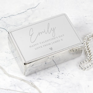 May include: Silver jewellery box with a personalised inscription that reads "Emily Happy Valentine's Day Love from James x" with a small heart symbol.