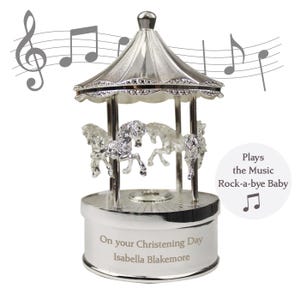 Peut inclure: Carrousel musical en argent avec quatre chevaux, joue la chanson "Dodo l'enfant do". La base est grav&eacute;e avec "On your Christening Day Isabella Blakemore".