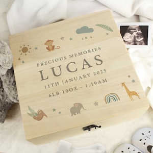 May include: A wooden keepsake box with a light wood finish and a light brown lid. The lid has a whimsical design with a sun, clouds, raindrops, stars, a monkey, a sloth, an elephant, a giraffe, and a rainbow. The box is personalised with the text "Precious Memories", "Lucas", "11th January 2025", and "6lb 10oz - 1.19am".