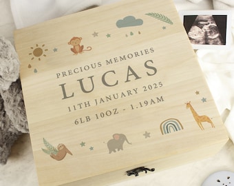 May include: A wooden keepsake box with a light wood finish and a light brown lid. The lid has a whimsical design with a sun, clouds, raindrops, stars, a monkey, a sloth, an elephant, a giraffe, and a rainbow. The box is personalized with the text "Precious Memories", "Lucas", "11th January 2025", and "6lb 10oz - 1.19am".