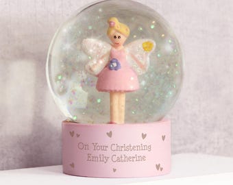 May include: Pink snow globe with a fairy figurine inside. The base of the snow globe has the text "On Your Christening Emily Catherine" on it.