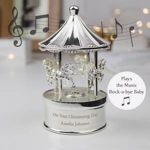 Peut inclure: Carrousel musical en argent avec des chevaux, joue "Dodo l'enfant do". Personnalis&eacute; avec "On Your Christening Day Amelia Johnson"