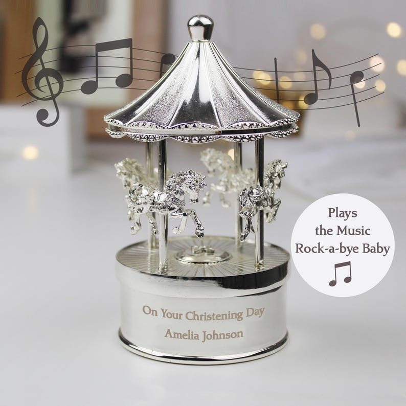 Peut inclure: Carrousel musical en argent avec des chevaux, joue "Dodo l'enfant do". Personnalis&eacute; avec "On Your Christening Day Amelia Johnson"