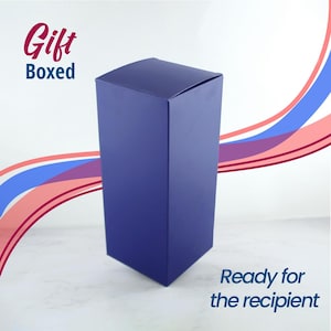 May include: A dark blue gift box, ready for the recipient. The box is on a white surface with a pink and blue background.