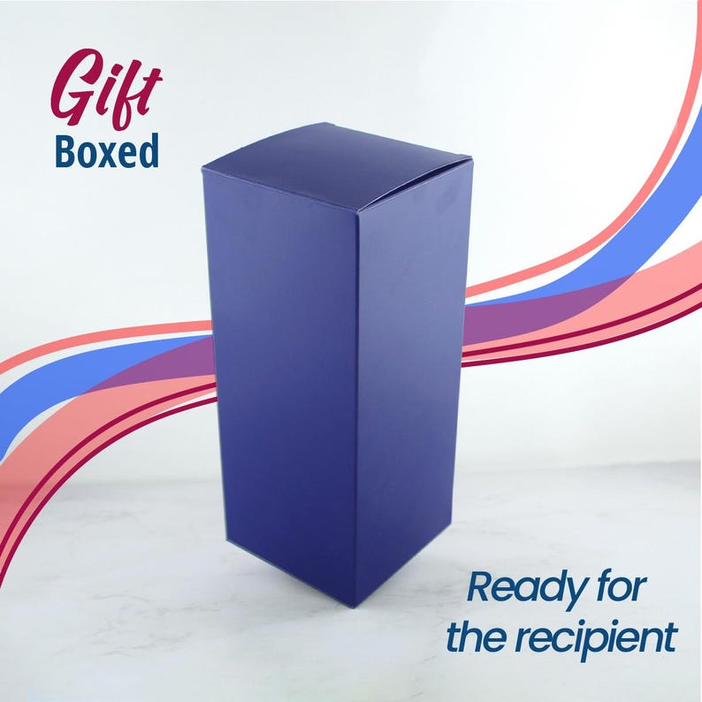 May include: A dark blue gift box, ready for the recipient. The box is on a white surface with a pink and blue background.