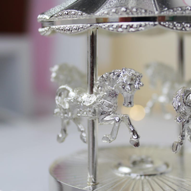 Peut inclure: Un carrousel argent&eacute; avec trois chevaux, un toit argent&eacute; et une base argent&eacute;e. Le carrousel est un objet d&eacute;coratif.