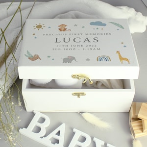 May include: White wooden keepsake box with a gold latch. The lid features a colorful illustration of animals, stars, and a rainbow. The text on the lid reads "Precious First Memories Lucas 11th June 2022 5lb 10oz - 1:19 AM".
