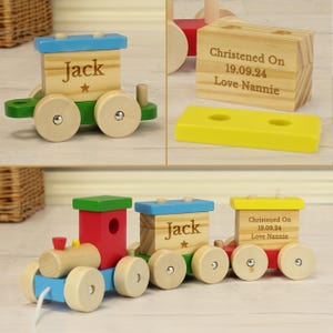 May include: A wooden toy train with three carriages. The first carriage is red with a hole in the side. The second carriage is blue with the name "Jack" on the side. The third carriage is yellow with the text "Christened On 19.09.24 Love Nannie".