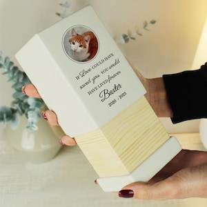 May include: White ceramic box with a wood top. The box has a photo of a cat and the text "If love could have saved you, you would have lived forever. Baxter 2020 - 2023"