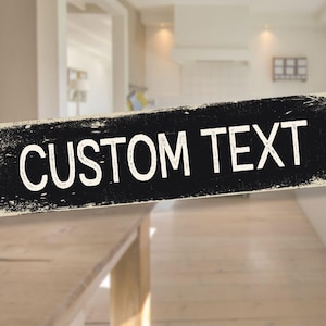 Può includere: Un cartello rettangolare in legno nero con le parole "CUSTOM TEXT" in bianco, con scritte invecchiate. Il cartello ha un aspetto invecchiato e vintage, con un bordo di colore chiaro.