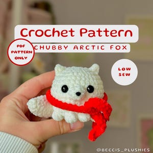 Könnte beinhalten: Häkelanleitung für einen weißen, pummeligen Eisfuchs mit rotem Schal. Das Muster ist für ein Projekt mit wenig Nähen. Der Text "PDF PATTERN ONLY" befindet sich in einem roten Kreis. Der Text "LOW SEW" befindet sich in einem roten Kreis. Der Text "@BECCIS_PLUSHIES" befindet sich am unteren Rand des Bildes.