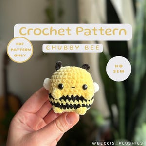 Könnte beinhalten: Ein Häkelmuster für eine kuschelige, nahtlose Amigurumi-Biene. Das Muster ist nur als PDF-Download erhältlich. Die Biene ist gelb und schwarz mit weißen Flügeln und einem süßen Gesicht.