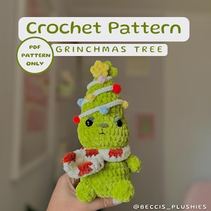 Könnte beinhalten: Ein Häkelmuster für einen Grinchmas-Baum, ein grüner gehäkelter Weihnachtsbaum mit einem mürrischen Gesicht, der einen rot-weißen Schal trägt. Das Muster ist nur als PDF-Download erhältlich.