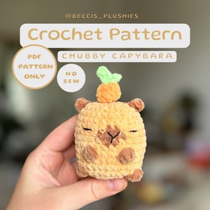 Könnte beinhalten: Häkelanleitung für ein pummeliges Capybara mit einer Karotte auf dem Kopf. Das Muster ist als PDF-Download erhältlich und ist nahtlos. Das Capybara ist in braunem und beigefarbenem Garn gehäkelt.