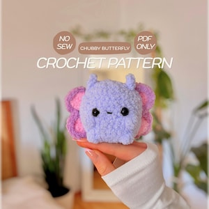 Könnte beinhalten: Ein hellviolettes und rosafarbenes gehäkeltes Schmetterlings-Plüschtier mit schwarzen Sicherheitsaugen und einem kleinen gestickten Mund. Der Text NO SEW, PDF ONLY, CHUBBY BUTTERFLY und CROCHET PATTERN steht in weißen und braunen Kreisen über dem Plüschtier.