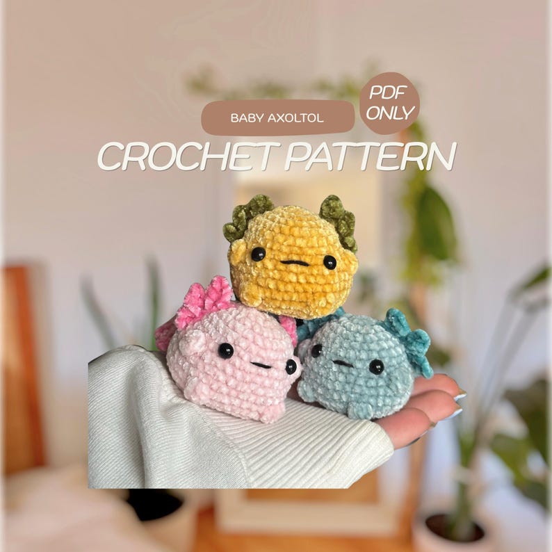 Peut inclure: Un mod&egrave;le de crochet PDF num&eacute;rique pour un b&eacute;b&eacute; axolotl repr&eacute;sentant trois petites cr&eacute;atures en peluche en fil textur&eacute; jaune, rose et bleu clair. Chaque axolotl a des yeux en perles noires et une bouche cousue simple, avec des branchies externes.
