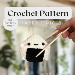 May include: A crochet pattern for a happy onigiri, a Japanese rice ball, with a smiling face. The onigiri is being held by chopsticks. The text "HAPPY ONIGIRI" is written above the onigiri.