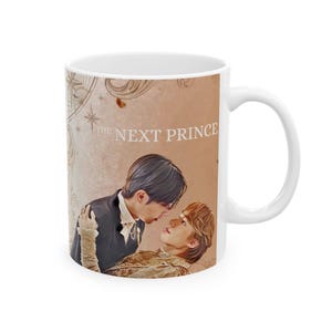 May include: White ceramic mug featuring a romantic illustration of two men gazing at each other. The mug has the text "THE NEXT PRINCE" printed on it, with a beige background and a white handle.