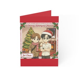 May include: Red Christmas card featuring an anime-style illustration of two people in front of a decorated Christmas tree and fireplace. The card reads "Merry Khemjira Mas" and "Jet Chan".